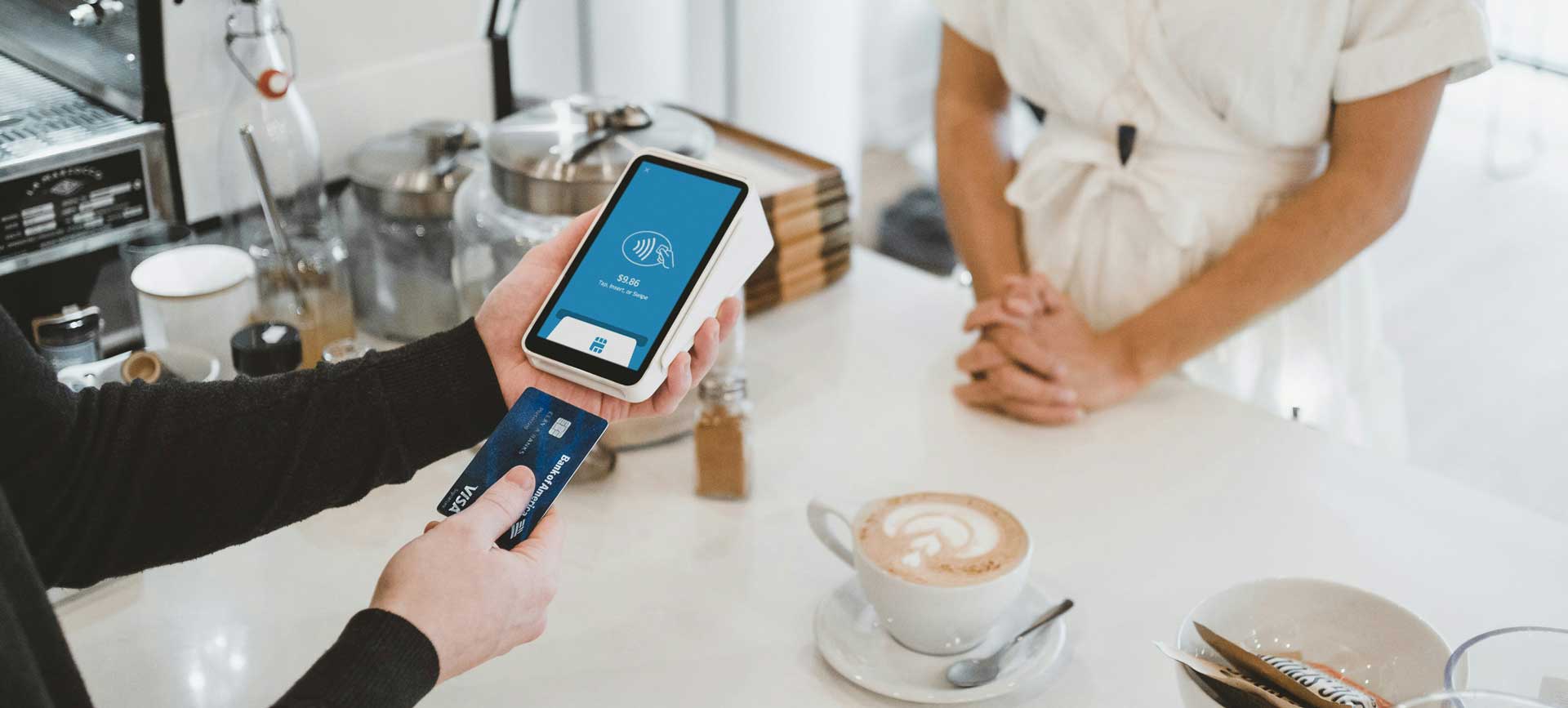 Cliente pagando com o cartão de crédito sua compra na cafeteria.